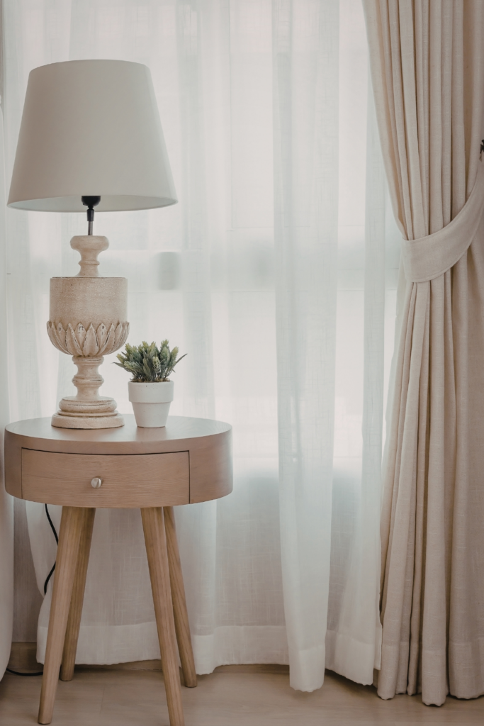 Bedside nightstand lamp with a warm glowing light next to a cozy bed, adding style, ambient lighting, and budget-friendly charm to the bedroom for under $50.