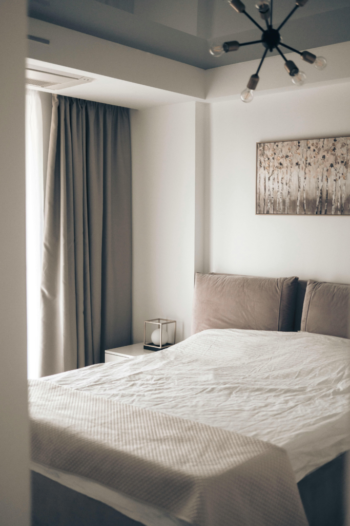 Neutral-colored blackout curtains hanging in a cozy bedroom, blocking light and adding style and comfort to the space for under $50.