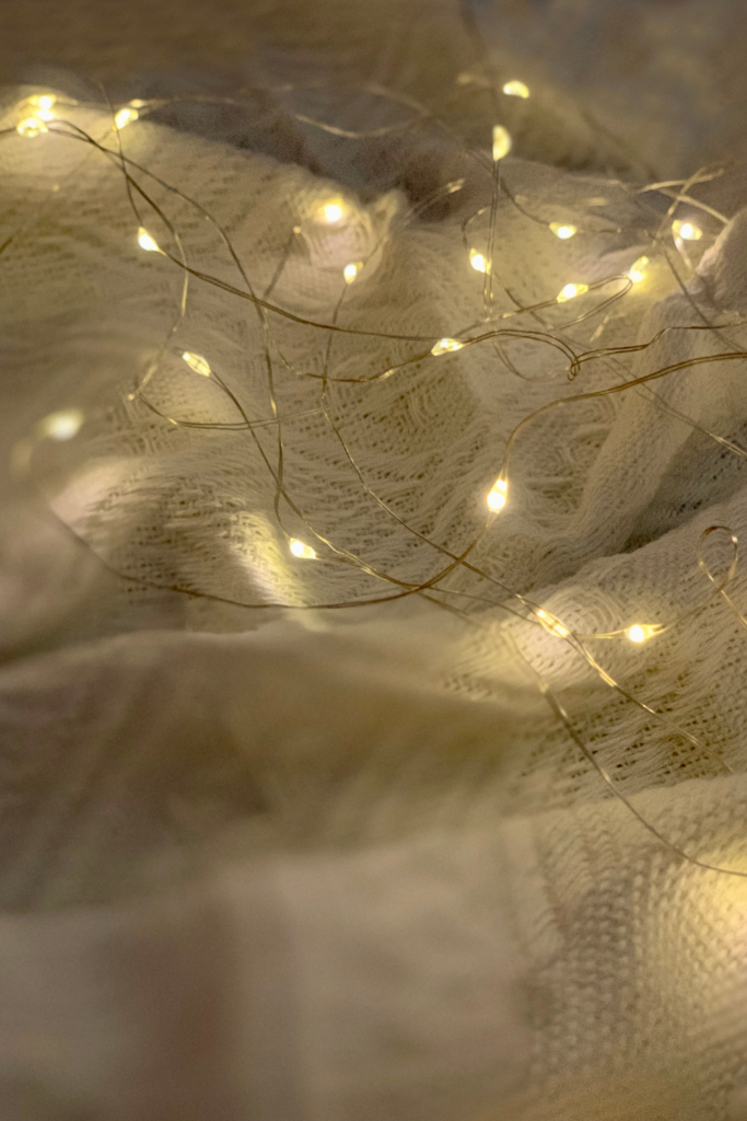 Warm LED string lights draped around a bed frame in a cozy bedroom, creating a soft, ambient glow and a budget-friendly, inviting atmosphere under $50.