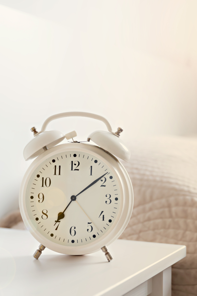 Sleek, minimalist alarm clock on a bedside table next to a cozy bed, adding modern style, functionality, and budget-friendly charm to the bedroom for under $50.