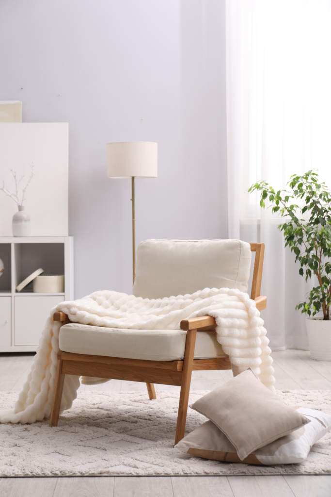 Soft neutral throw blanket draped over a sofa, adding warmth and texture for a cozy spring living room.