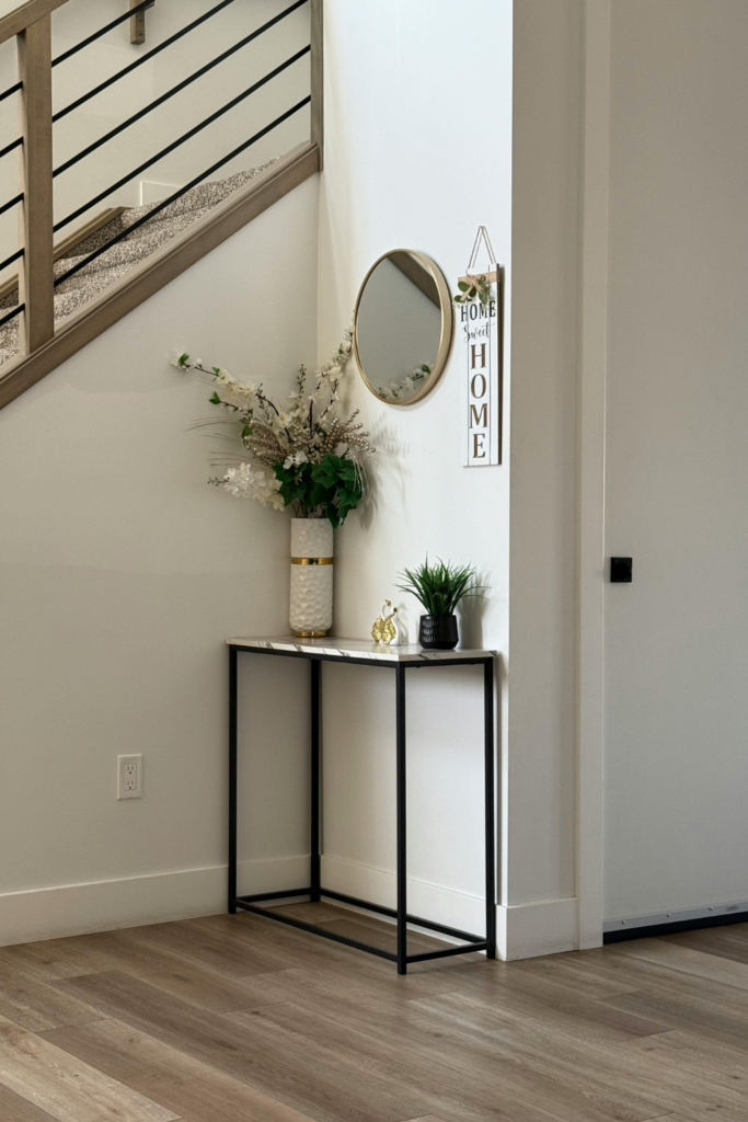 Wall display mirror with a decorative frame in an entryway, reflecting light and adding stylish, modern, and budget-friendly home decor.