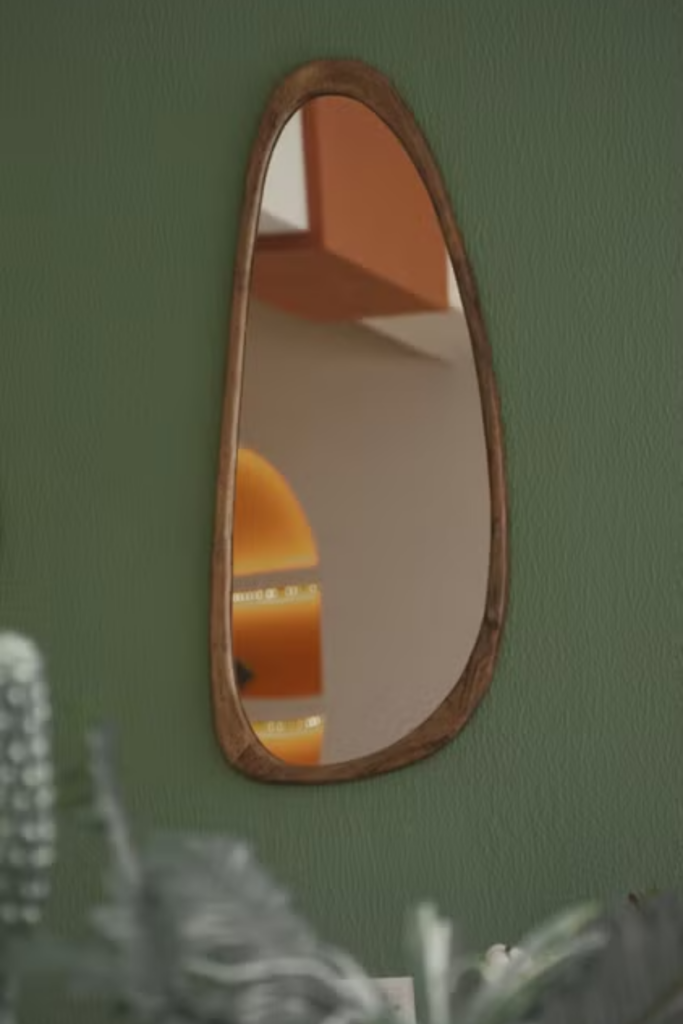 asymmetric walnut wood framed irregular wall mirror on dark green wall