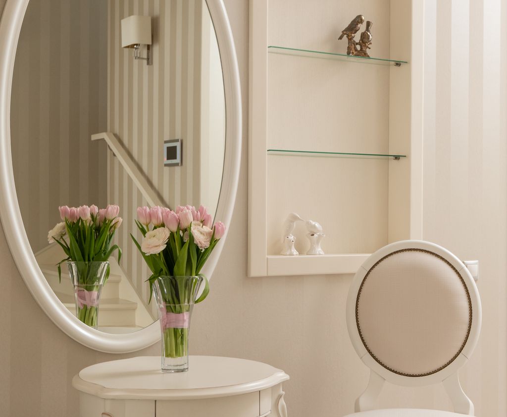 Fresh aromatic bouquet placed on light table near mirror in stylish room in daytime